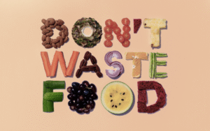 Text 'DON'T WASTE FOOD' spelled out with colorful fruits, vegetables, and nuts. This image highlights the concept of avoiding food waste, a key principle of Waste in Islam.